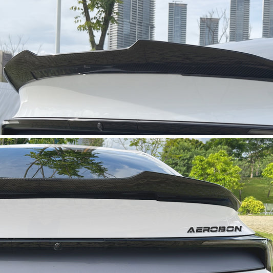 A carbon fiber rear trunk spoiler shown installed on the trunk of a white car, with a top view in an urban setting and a bottom view in a park setting. The Aerobon brand name is visible on the rear badge.